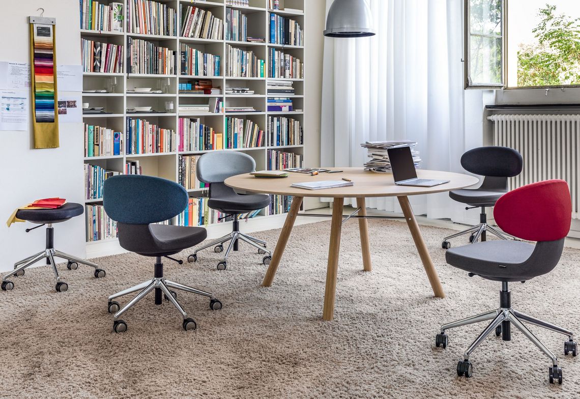 Besprechungstisch Massivholz rund mit Schreibtischstühlen verschiedenfarbig gepolstert im Besprechungszimmer