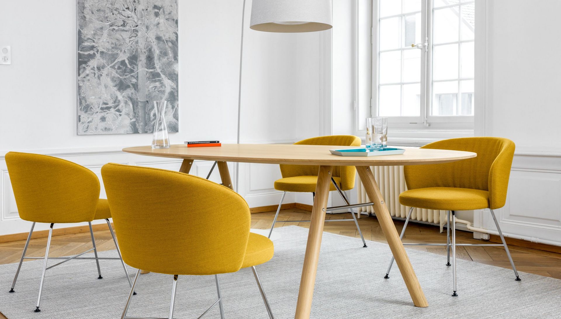 Akio Esstisch Massvivolz in Eiche mit Biala Vierbeinstuhl blau gepolstert im Wohnzimmer