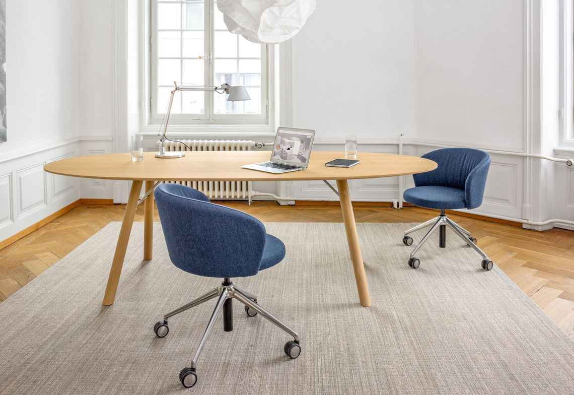 Ovaler Schreibtisch in Massivholz Eiche mit Konferenzstuhl blau gepolstert am Arbeitsplatz