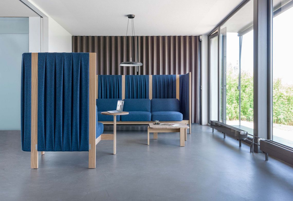 Dreisitzer Loungesofa und Sessel blau gepolstert mit Seitenpaneelen im Wartebereich