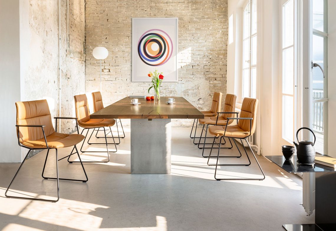 Kufenstuhl Stahl schwarz mit hellem Leder gepolstert am Esstisch