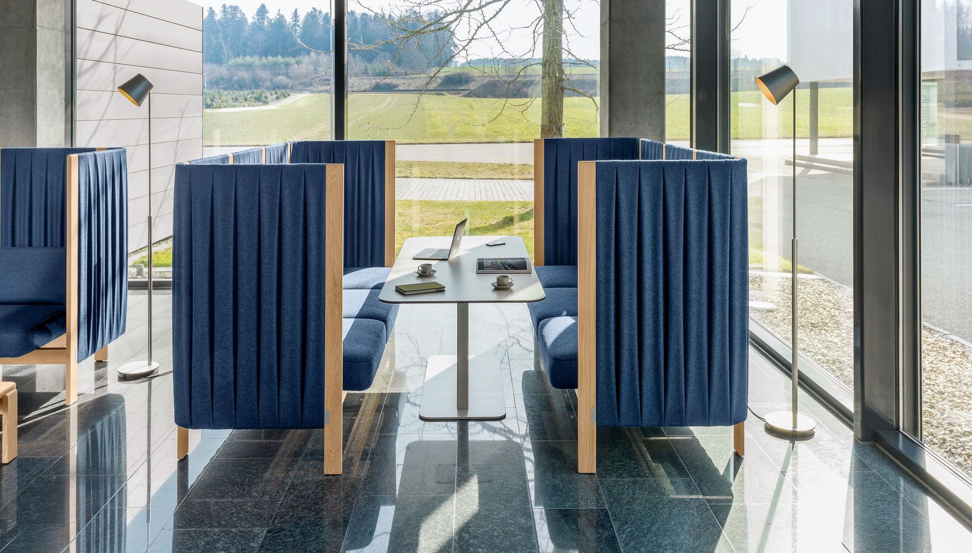 Velum Arbeitstisch mit silber beschichtetem Gestell und weisser Vollkernplatte mit Velum Dreisitzer Sofa mit Seitenpaneelen in blau gepolstert in der Empfangshalle