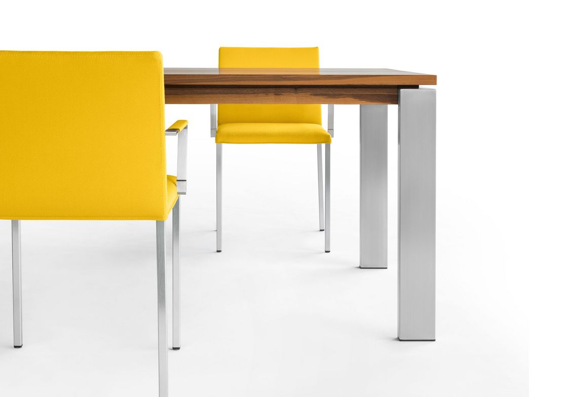 Nahaufnahme ausziehbarer Tisch Massivholz und zwei gelb gepolsterte Stühle