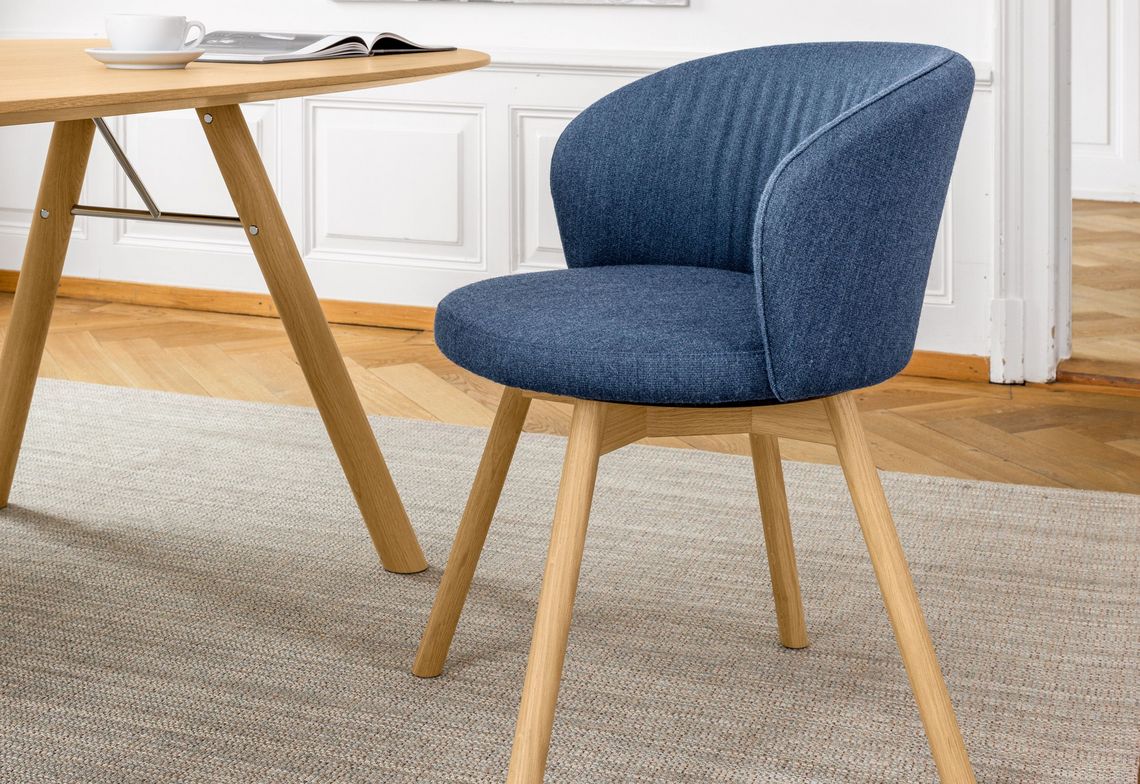 Gepolsterter Esszimmerstuhl in blau mit Holzgestell am runden Esstisch Akio