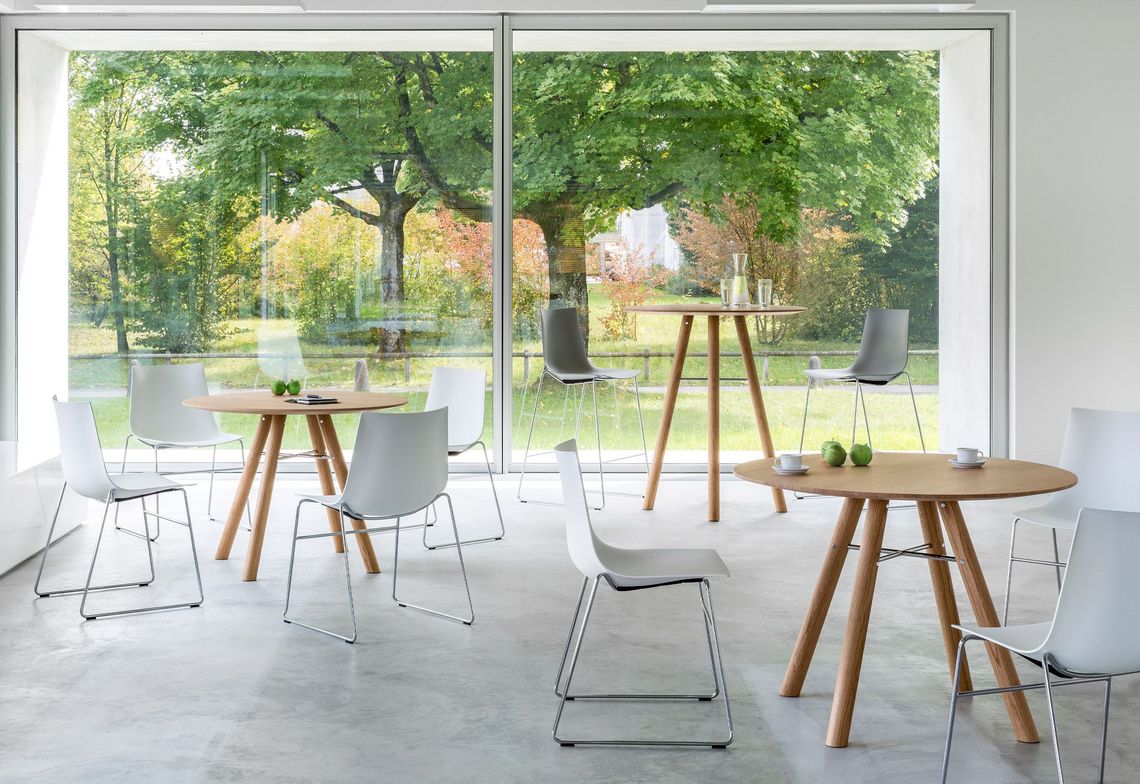Runde Besprechungstische in Eiche mit Kufenstühlen mit weisser Sitzschale in der Begegnungszone