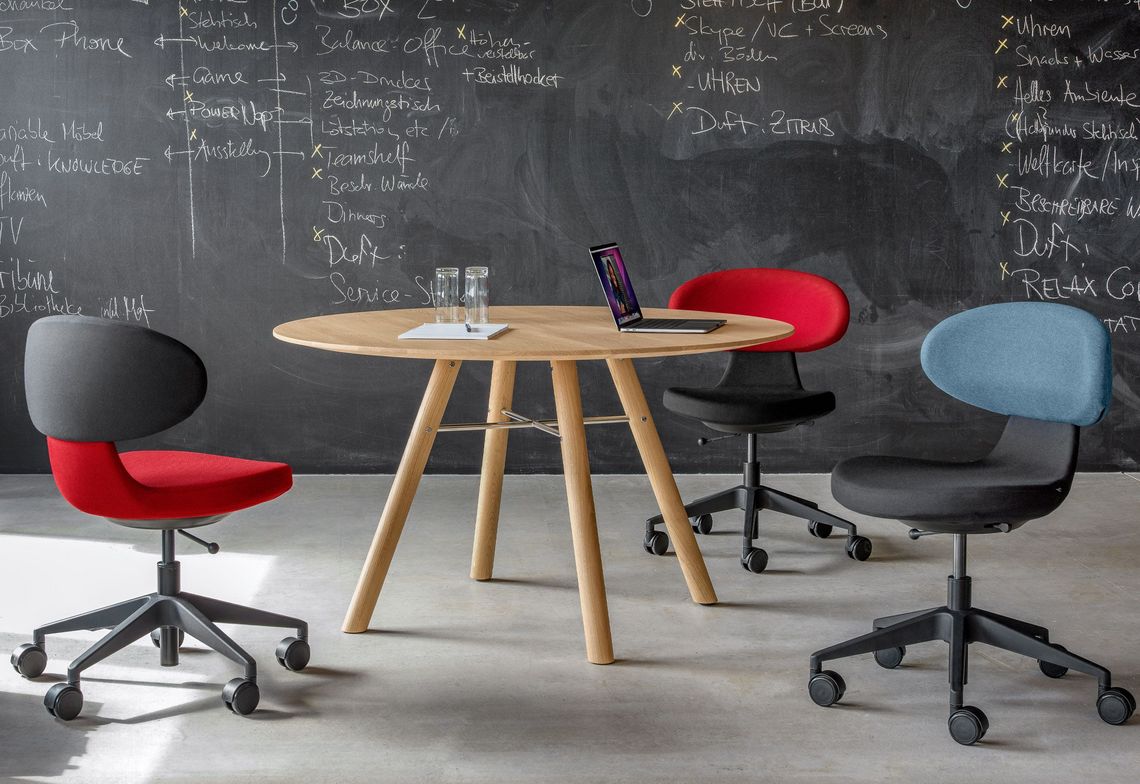 Massivholztisch rund im Besprechungsraum mit Bürostuhl mit verschieden farbiger Polsterung