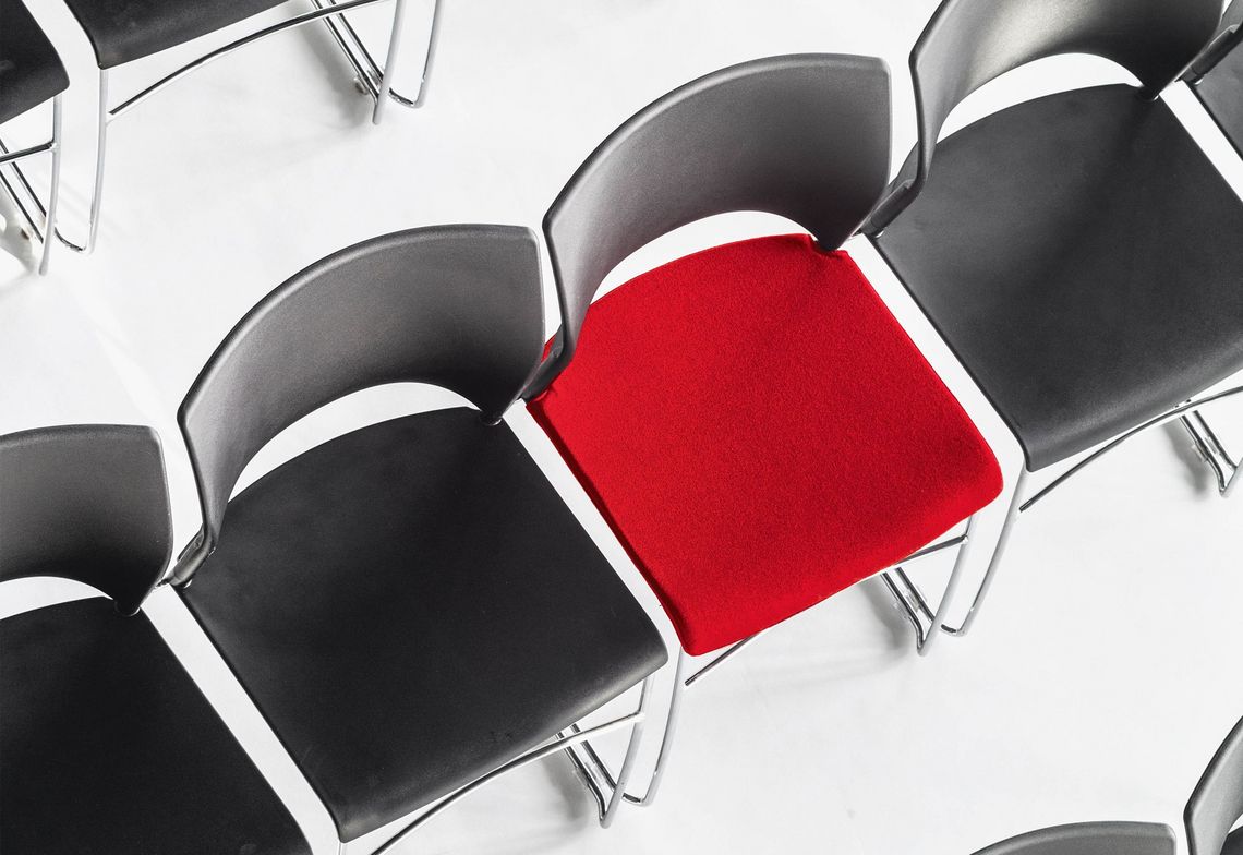 Stapelstuhl in Reihe verkettbar, mit schwarzer Kunststoffschale und rotem Sitzpolster