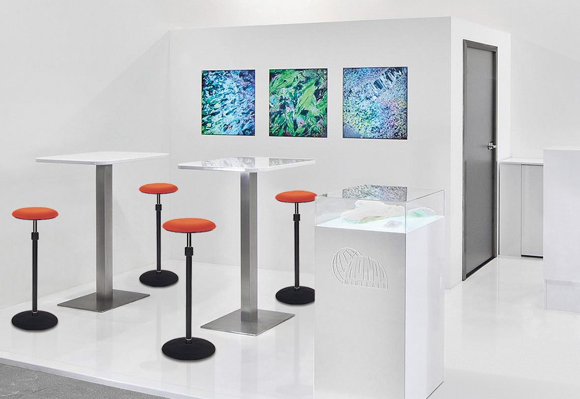 Stehsitz mit orangem Sitzpolster im Besprechungsbereich an einer Ausstellung